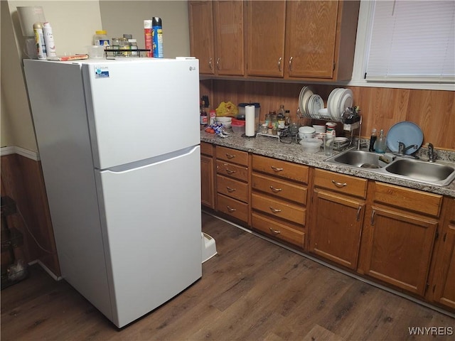 kitchen with a sink, dark wood-style floors, brown cabinets, and freestanding refrigerator