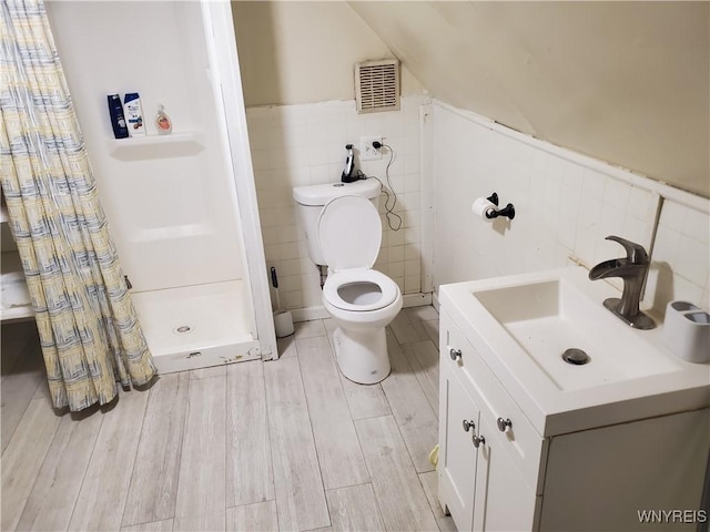 bathroom with a shower stall, visible vents, toilet, tile walls, and wood finished floors