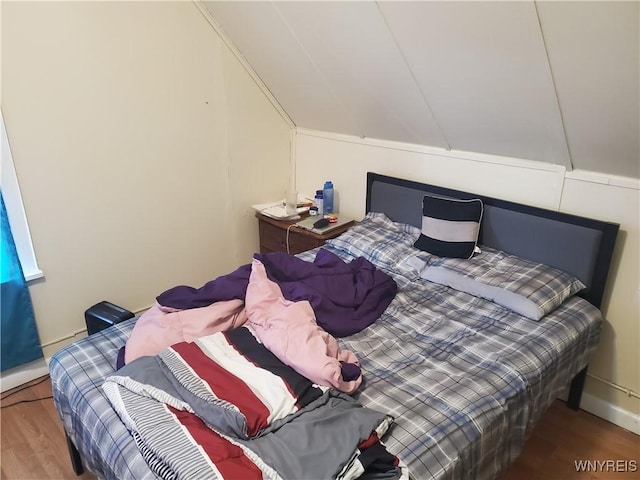 bedroom featuring wood finished floors, vaulted ceiling, and baseboards