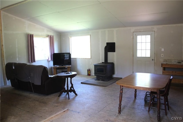 living area with vaulted ceiling and a wood stove