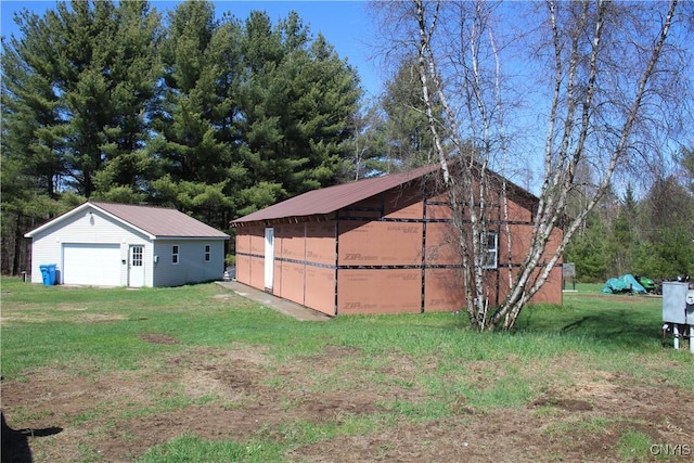 view of property exterior featuring metal roof, a yard, an outbuilding, and a garage