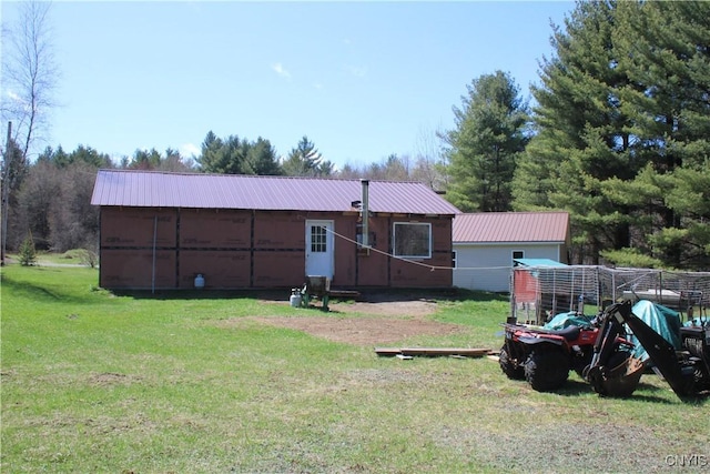 rear view of house with an outdoor structure, a pole building, a yard, and metal roof