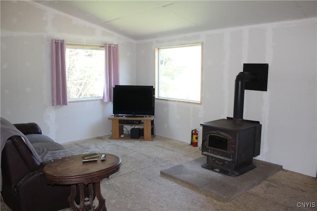living room featuring a wood stove, a healthy amount of sunlight, and lofted ceiling