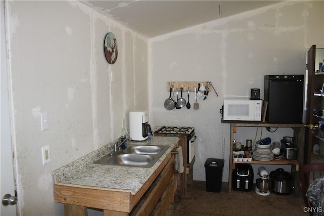 kitchen with a sink, white microwave, gas range, and light countertops