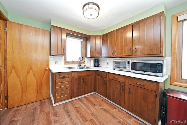 kitchen with stainless steel microwave, a sink, a wealth of natural light, and light countertops
