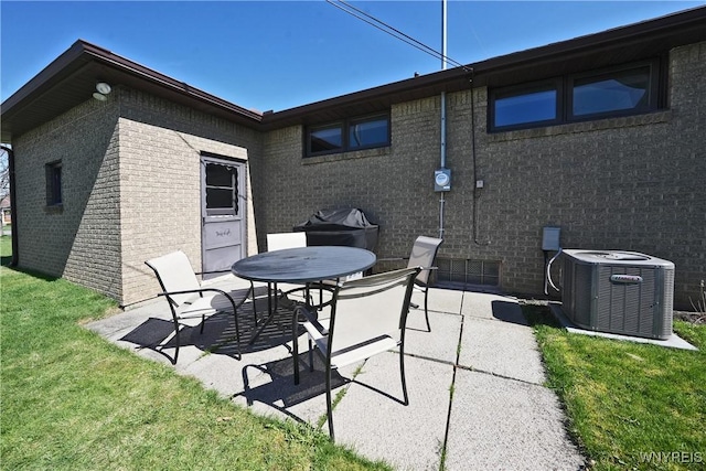 back of house with a lawn, brick siding, central AC unit, and a patio area