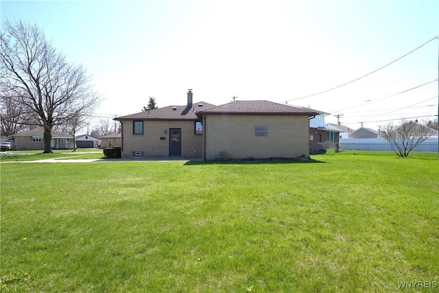 rear view of house with a lawn, brick siding, and a chimney
