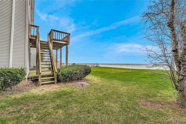 view of yard featuring a beach view, a deck with water view, and stairs