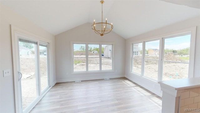 unfurnished dining area with a healthy amount of sunlight, a notable chandelier, vaulted ceiling, and light wood-style floors