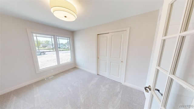 unfurnished bedroom with a closet, visible vents, carpet floors, and baseboards