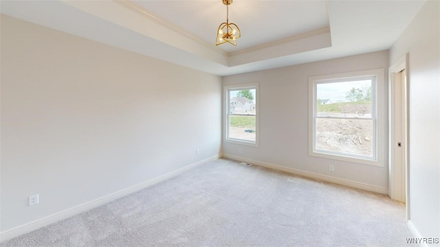 empty room featuring light colored carpet, a chandelier, and baseboards