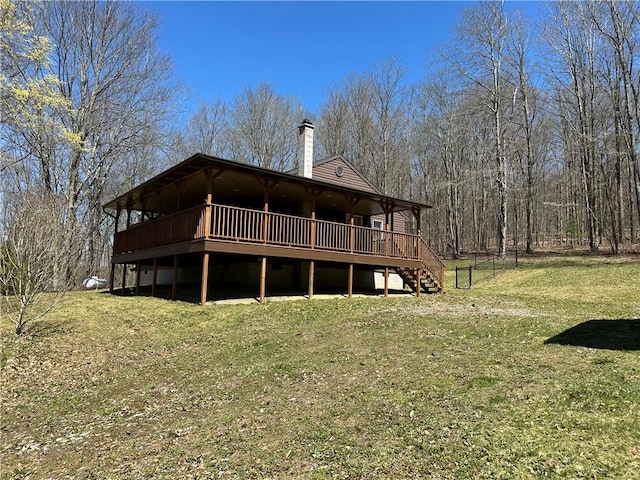 rear view of house featuring a chimney, stairway, a wooden deck, and a yard