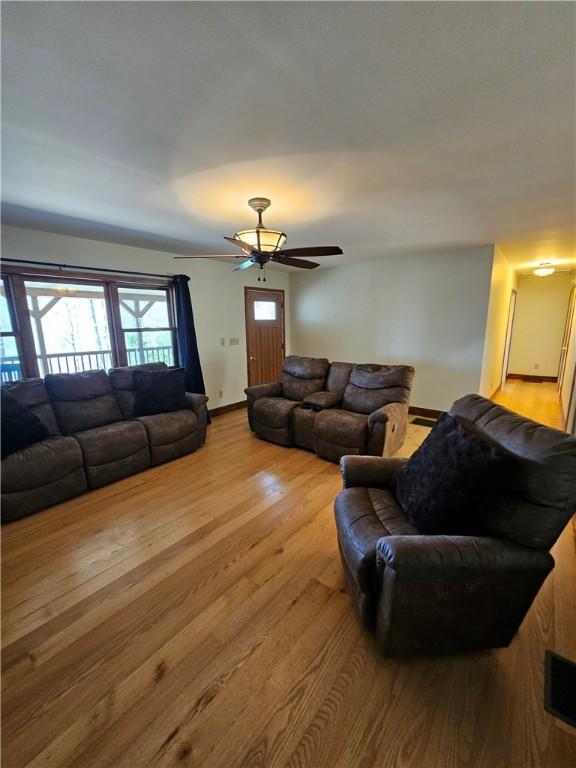 living area featuring a ceiling fan, wood finished floors, and baseboards
