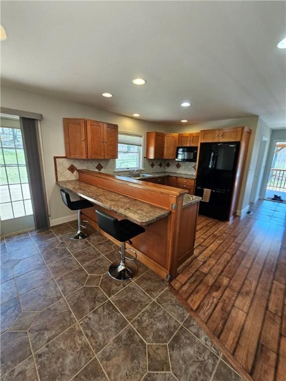 kitchen featuring black appliances, backsplash, plenty of natural light, and baseboards