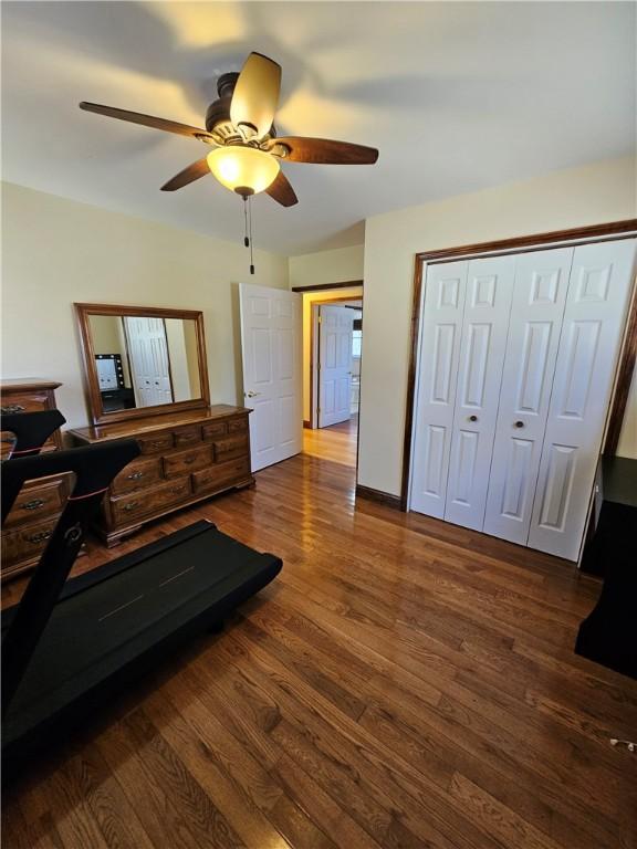 living area with dark wood-type flooring and ceiling fan