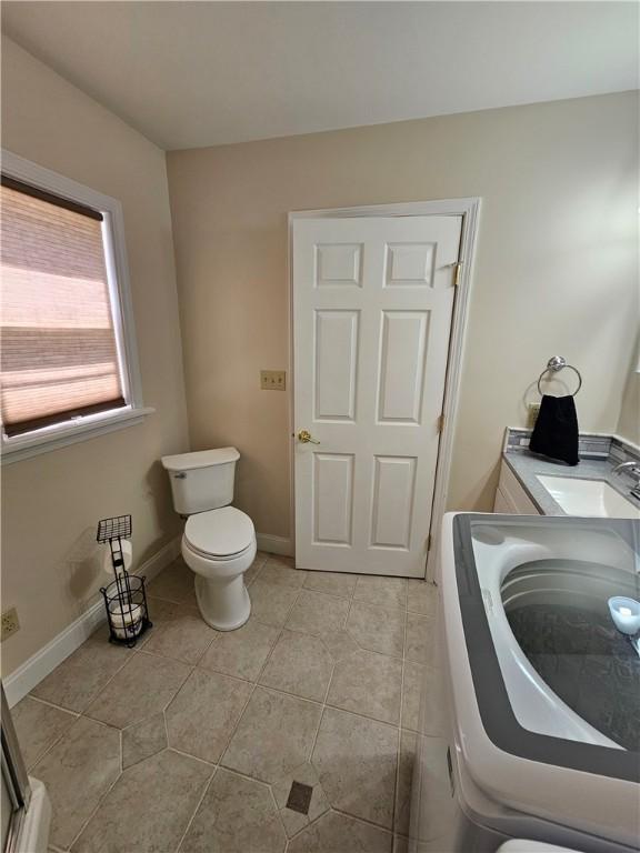 full bath with tile patterned floors, toilet, washer / clothes dryer, and a sink
