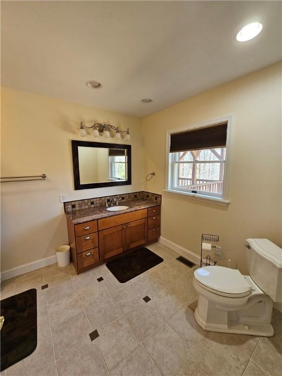 bathroom with vanity, toilet, visible vents, baseboards, and tile patterned flooring