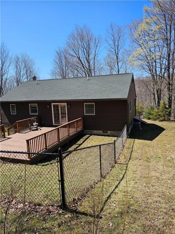 back of property featuring fence, roof with shingles, a lawn, and a wooden deck