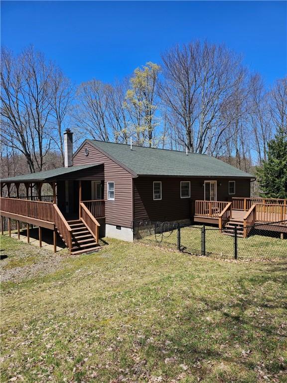 rear view of property featuring a wooden deck, a chimney, stairway, a yard, and a sunroom