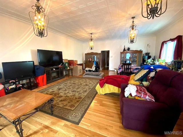 living area with a chandelier, ornamental molding, and wood finished floors