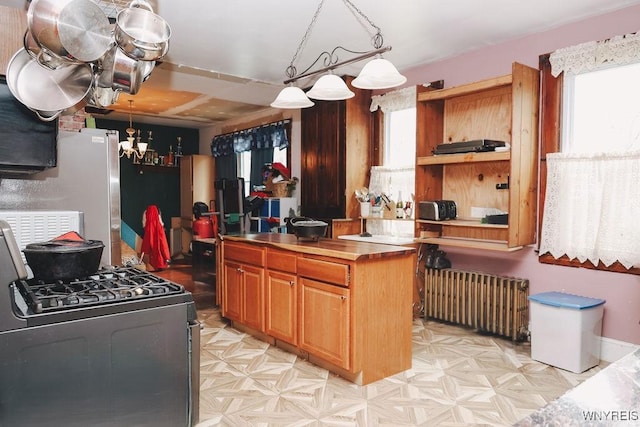 kitchen featuring hanging light fixtures, open shelves, radiator heating unit, gas stove, and a notable chandelier