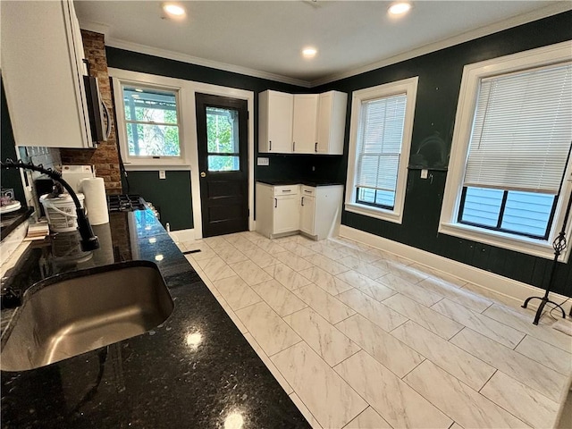 kitchen with stainless steel microwave, crown molding, white cabinets, and baseboards