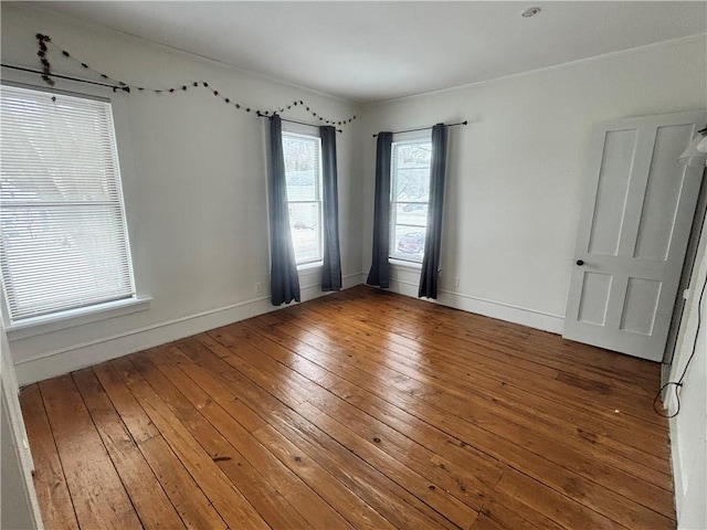 unfurnished room with baseboards and hardwood / wood-style flooring
