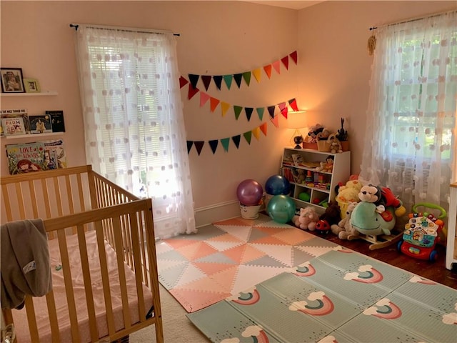 bedroom with multiple windows, a nursery area, and baseboards