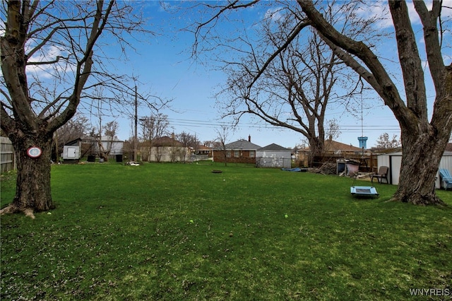 view of yard with a storage shed, fence, and an outdoor structure