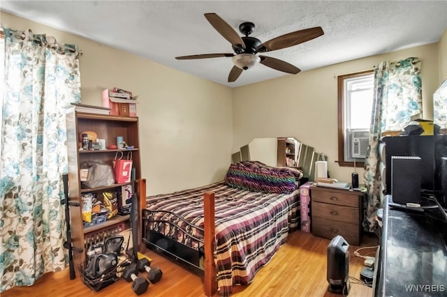 bedroom featuring ceiling fan, wood finished floors, and cooling unit