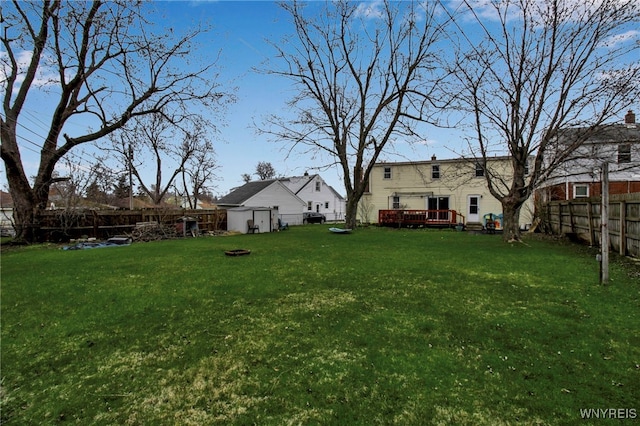 view of yard featuring a wooden deck, a fenced backyard, and an outdoor fire pit