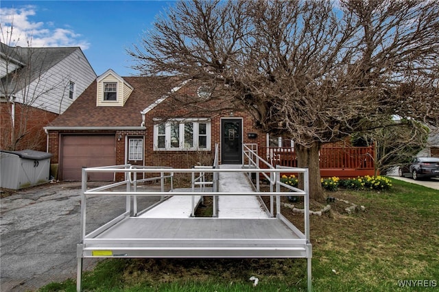 view of front facade with a garage, aphalt driveway, roof with shingles, and brick siding
