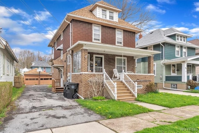 american foursquare style home with an outbuilding, a detached garage, and covered porch