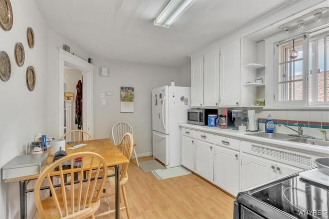 kitchen featuring range with electric cooktop, white cabinets, freestanding refrigerator, and a sink