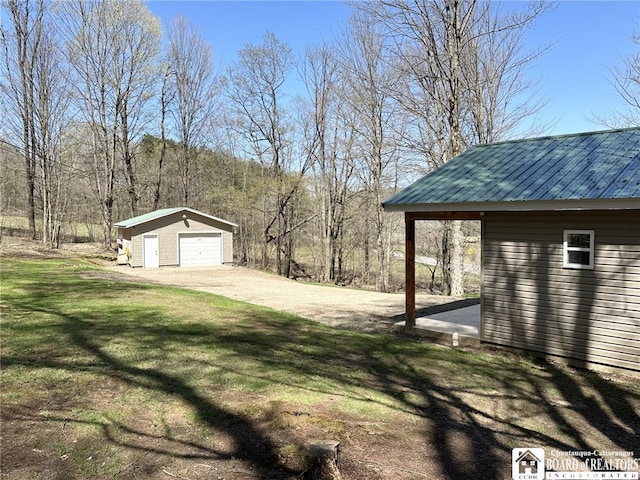 view of yard with a detached garage, an outbuilding, and driveway