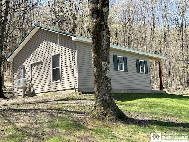 view of side of home featuring ac unit, a view of trees, and a lawn