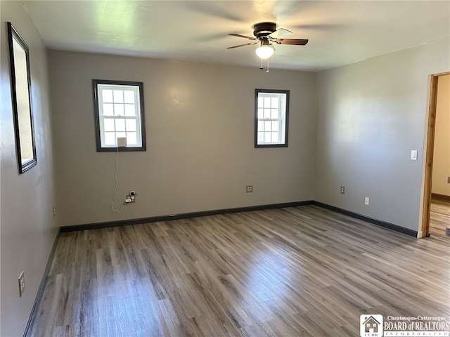 spare room with wood finished floors, ceiling fan, and baseboards