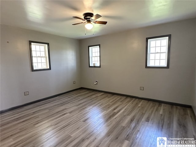 empty room with wood finished floors, ceiling fan, and baseboards