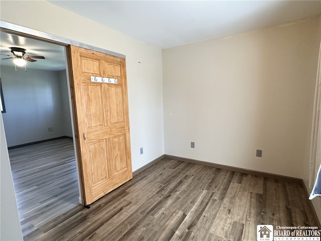 unfurnished room with dark wood-style floors, a ceiling fan, and baseboards