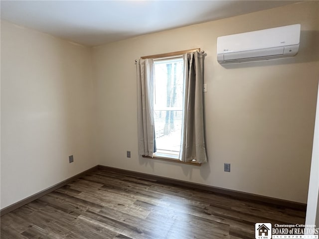 empty room featuring dark wood-style floors, a wall mounted AC, and baseboards