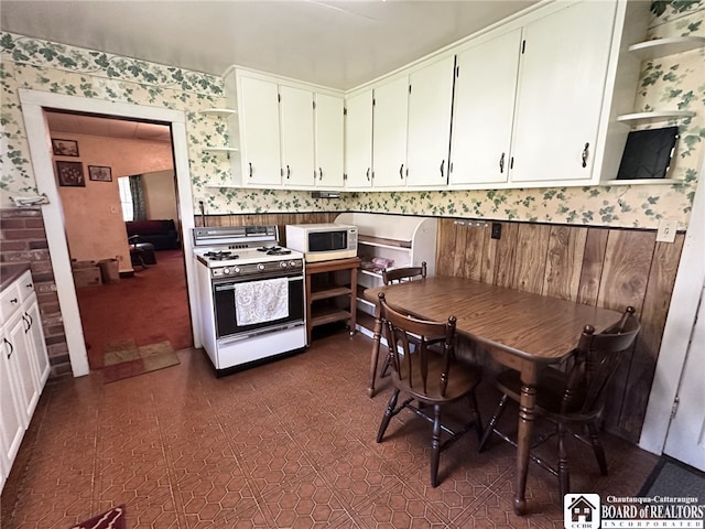 kitchen featuring white cabinets, wallpapered walls, open shelves, and white appliances