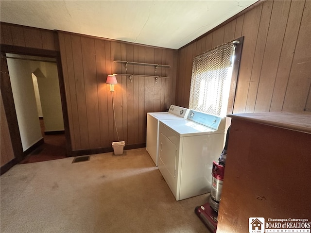 laundry room featuring wood walls, light colored carpet, visible vents, washer and clothes dryer, and laundry area