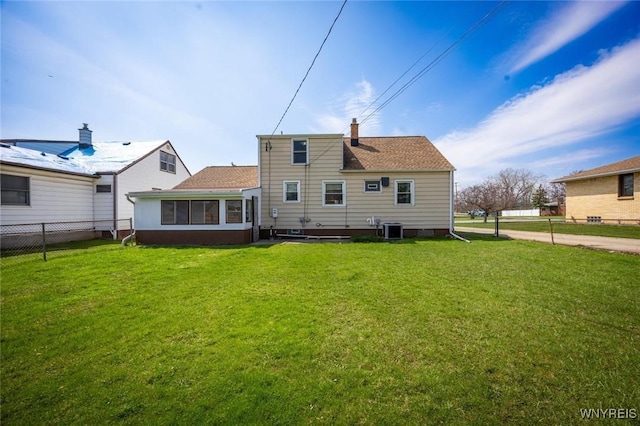 back of property featuring a lawn, central AC unit, a sunroom, and fence