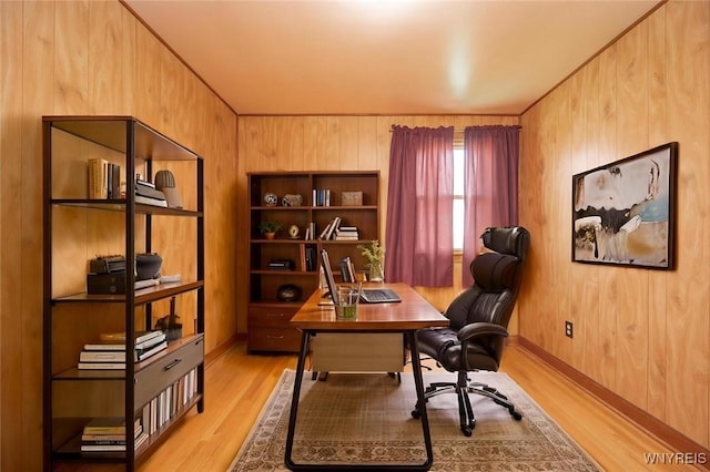 office area featuring wooden walls, light wood-type flooring, and baseboards
