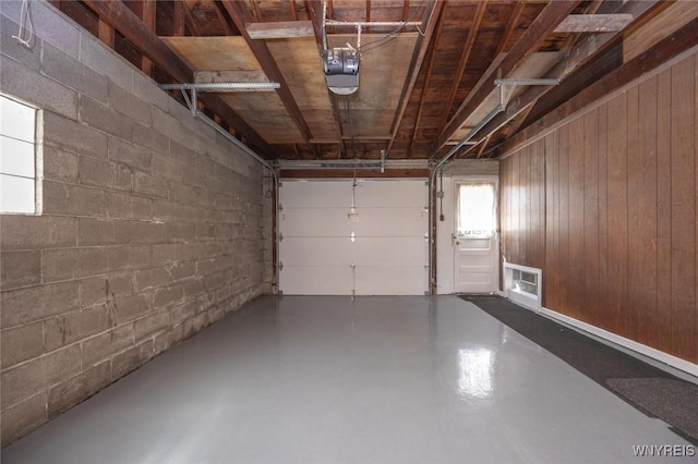 garage featuring a garage door opener and concrete block wall