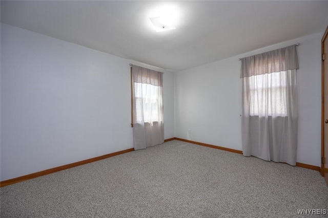 unfurnished room with light colored carpet and baseboards