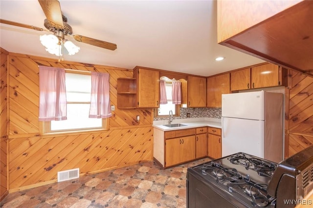 kitchen featuring a sink, black gas stove, visible vents, light countertops, and freestanding refrigerator