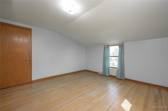 additional living space with visible vents, light wood-style floors, lofted ceiling, and baseboards