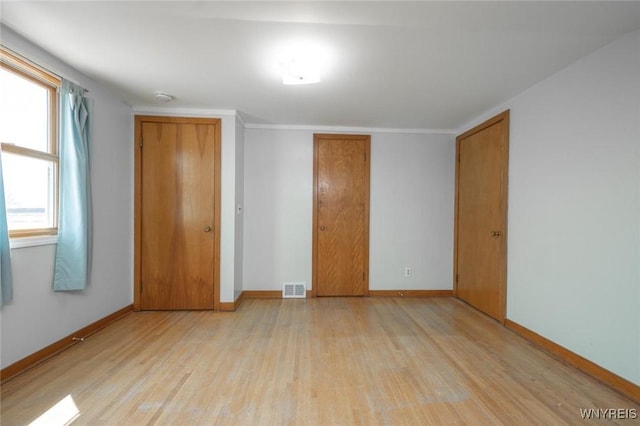 unfurnished bedroom featuring baseboards, visible vents, light wood-style floors, and a closet