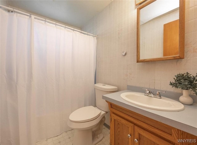 bathroom with toilet, tile walls, vanity, and tasteful backsplash